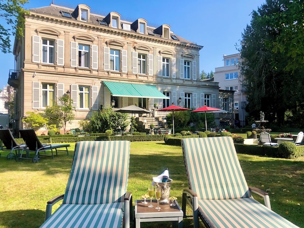 Un edificio grande e histórico con un patio que incluye asientos al aire libre y una fuente.