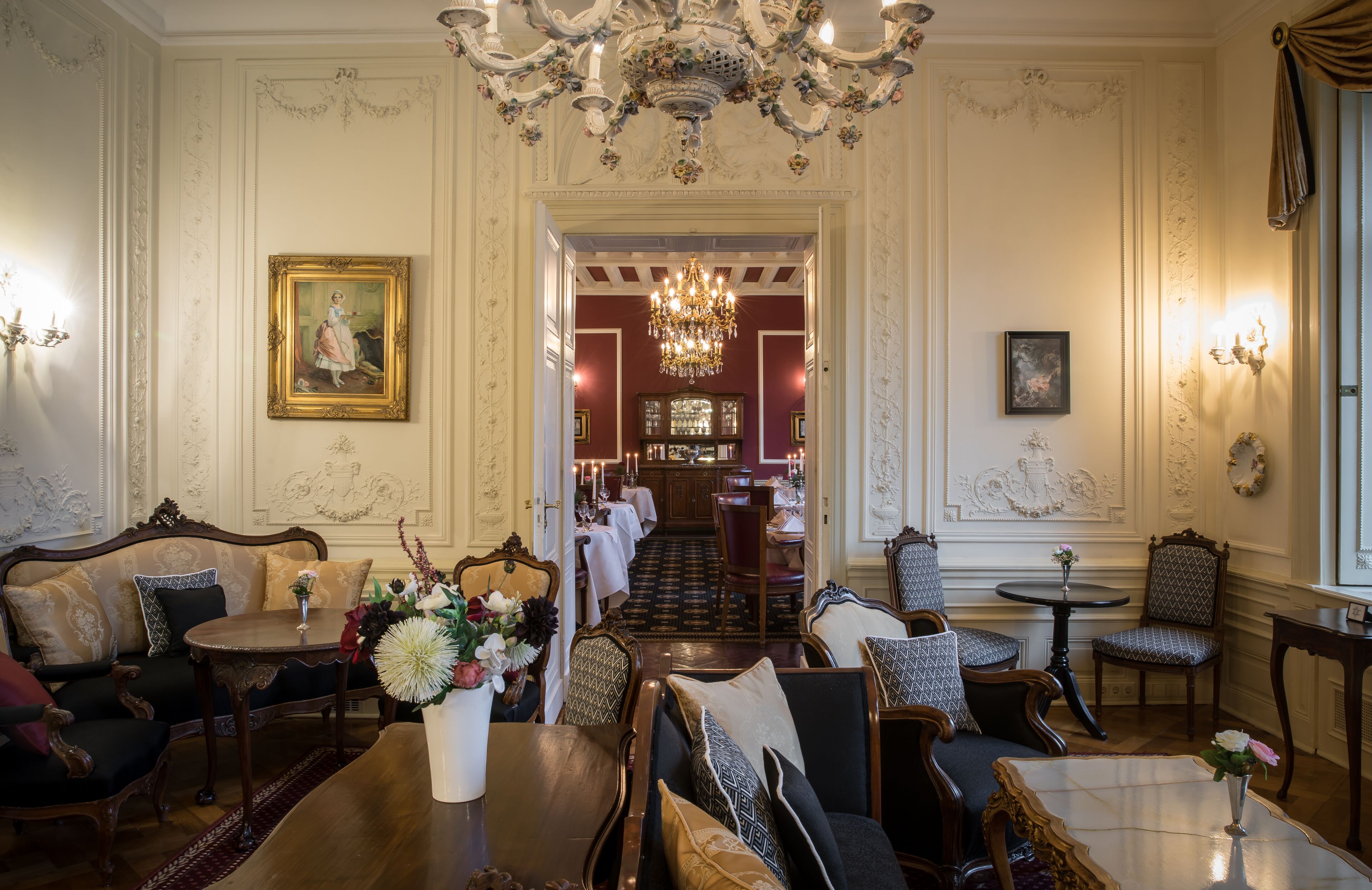 A formal dining room with a chandelier, ornate furniture, and a view into a dining area.