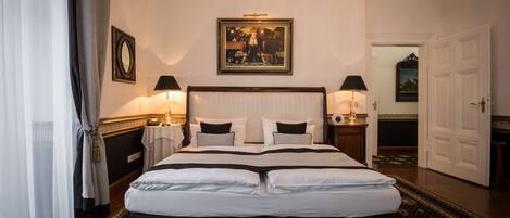 A neatly made bed with a white and black bedspread, two bedside lamps, a framed picture above the bed, and a patterned carpet.