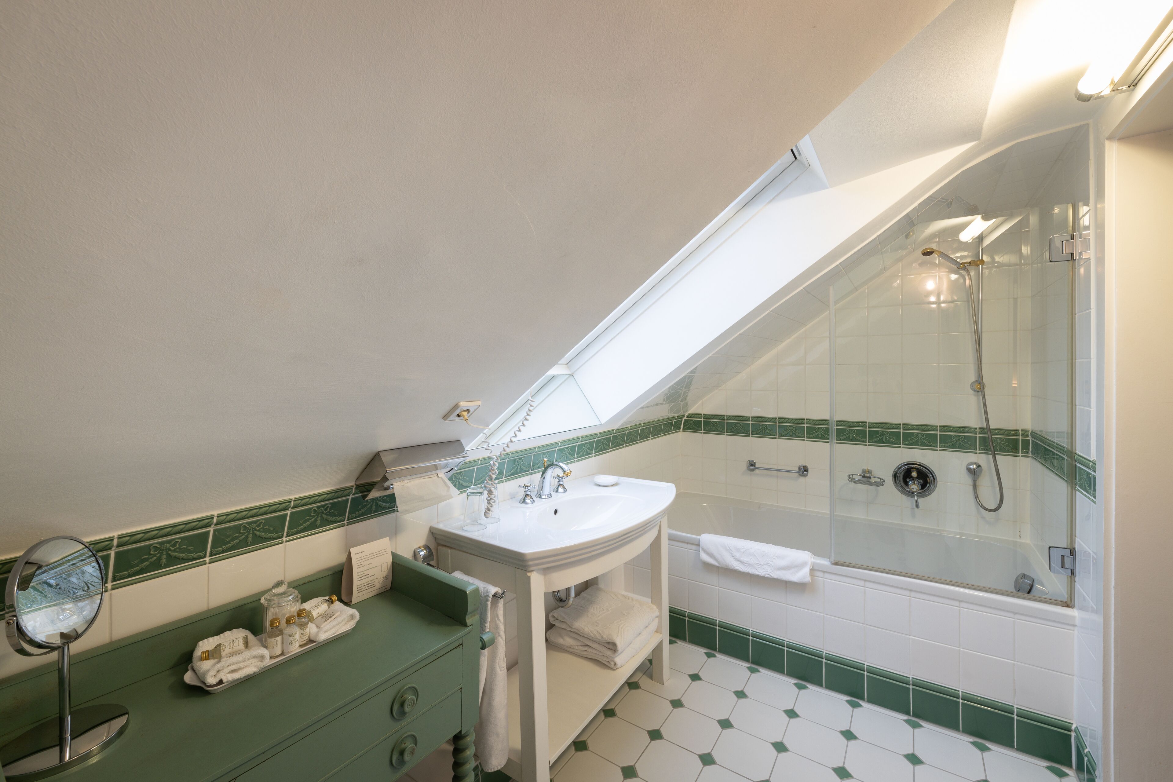 Un baño con tragaluz, lavamanos, espejo y ducha.