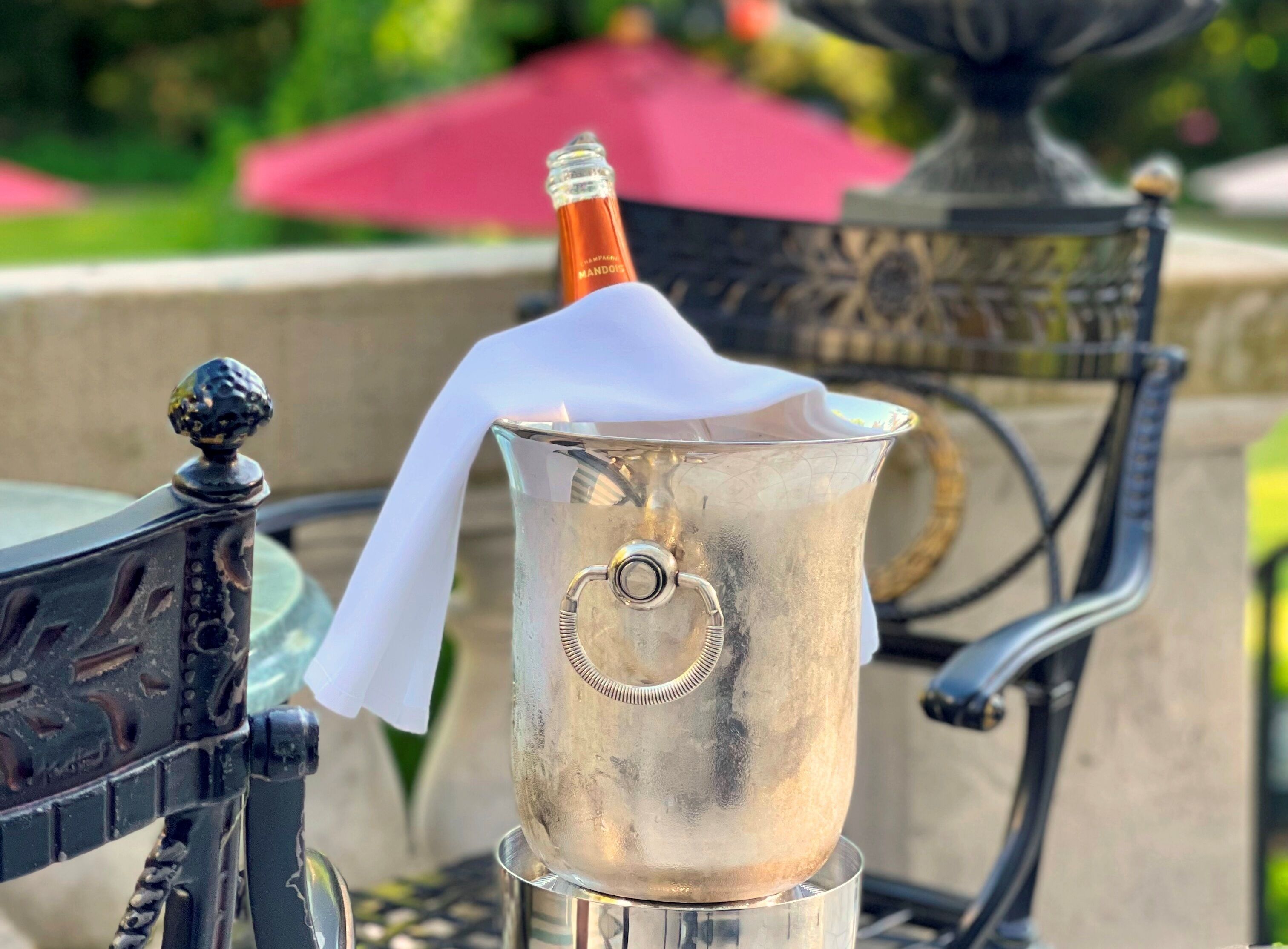 A metallic bucket with a bottle of champagne and a white napkin.