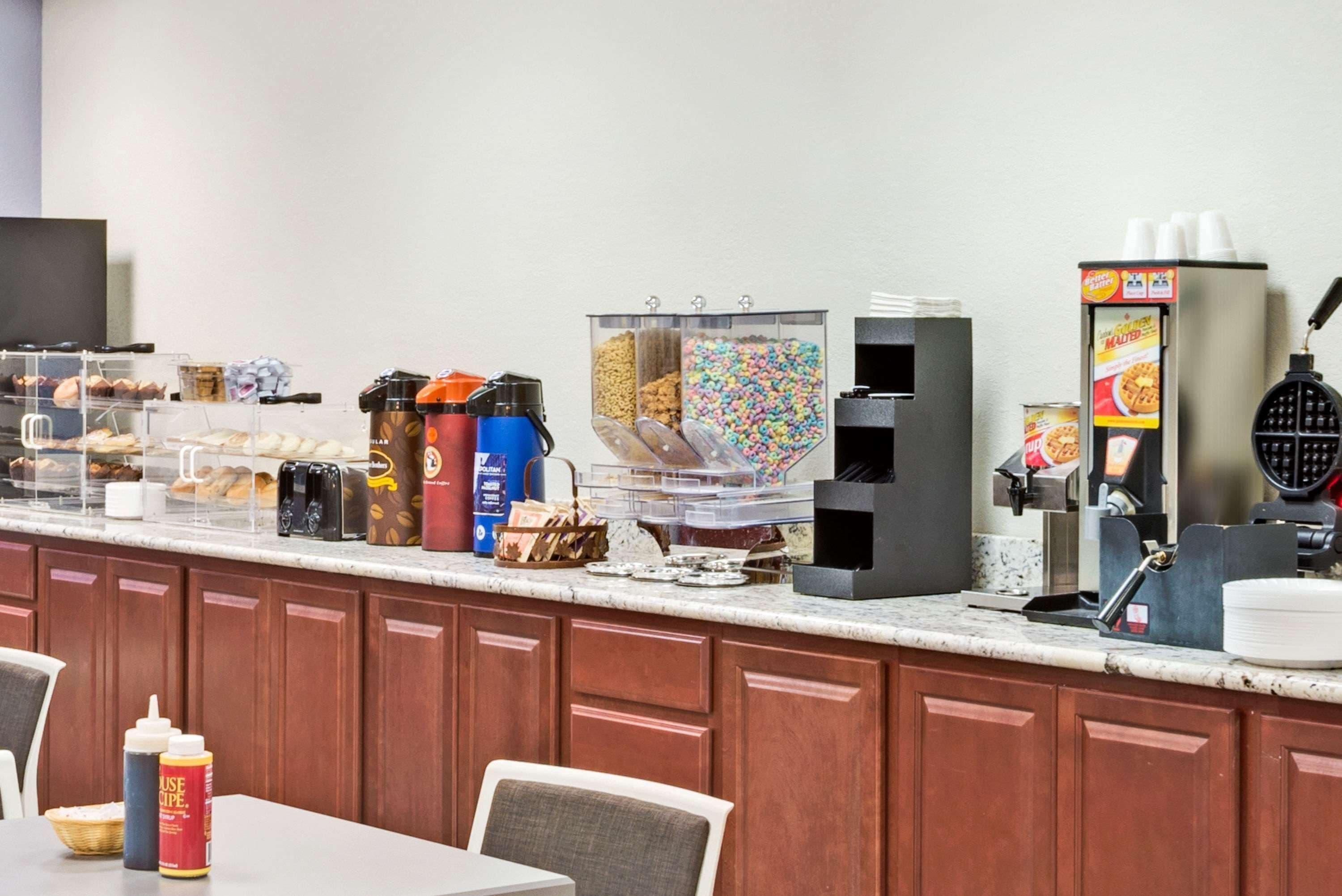 A breakfast bar with various food items, coffee machines, and condiments.