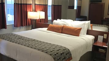 A hotel room with a large bed, a bedside table, a lamp, a mirror, and a window with curtains.