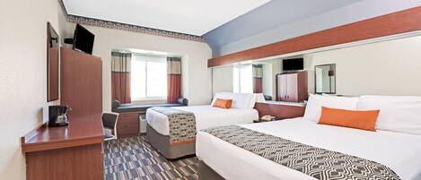 A hotel room with a bed, a desk, a chair, a television, and a window with curtains.