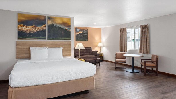 Ein Hotelzimmer mit einem großen Bett, einem Schreibtisch, zwei Stühlen und drei Bildern an der Wand.