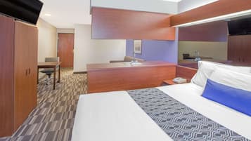 A hotel room with a bed, a desk, a chair, and a wardrobe.