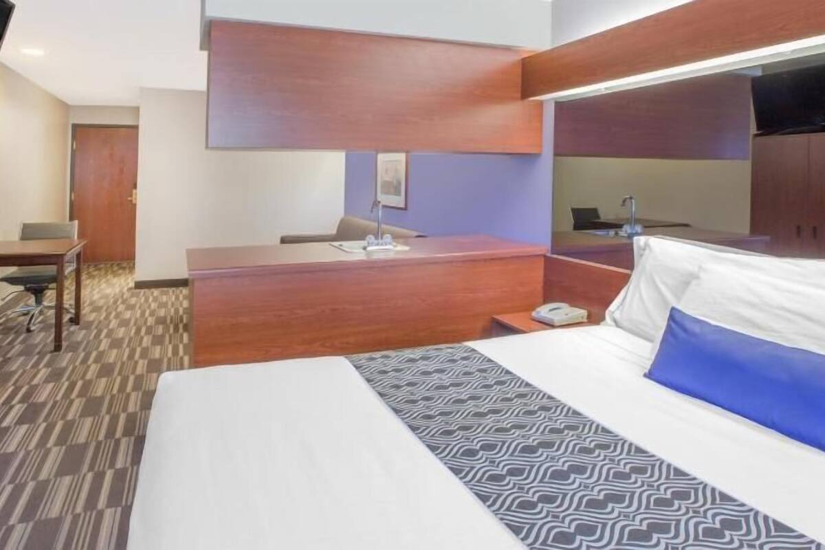 A hotel room with a bed, desk, chair, and wardrobe.