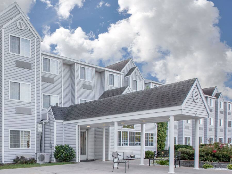 A multi-story building with a covered outdoor seating area, a wheelchair-accessible sign, and a car parked nearby.