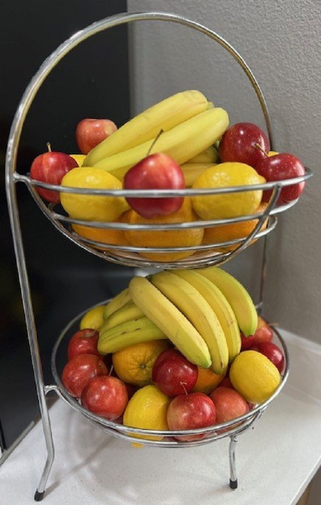 Un présentoir en métal contenant des pommes et des bananes.