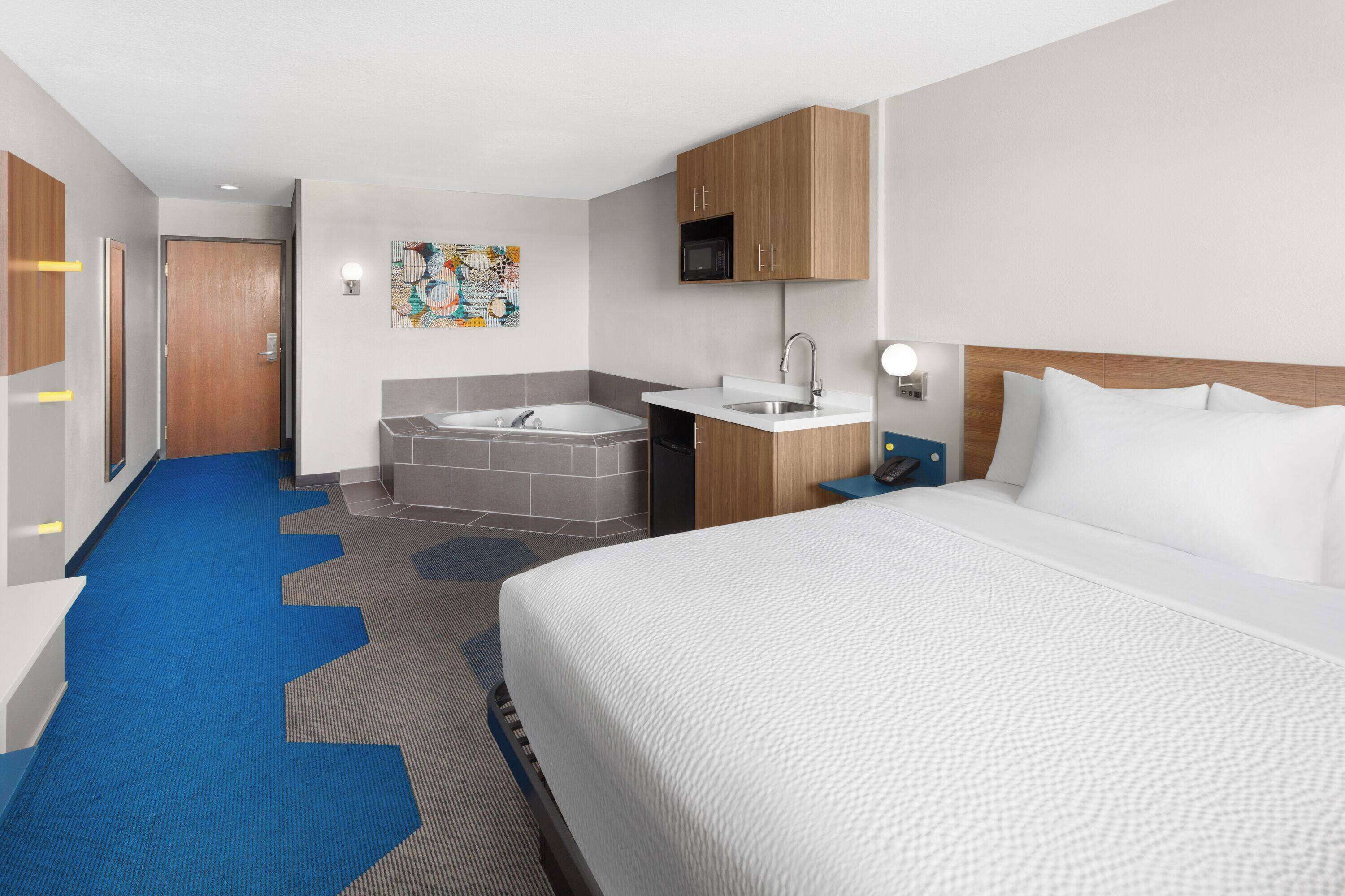 Une chambre d’hôtel avec un grand lit, une salle de bain avec une baignoire, un lavabo et un four à micro-ondes.