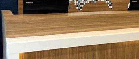 Un mostrador de recepción con detalles de madera y un panel frontal blanco.