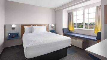 Een hotelkamer met een groot bed, een bureau, een raam met gordijnen en uitzicht op buiten.