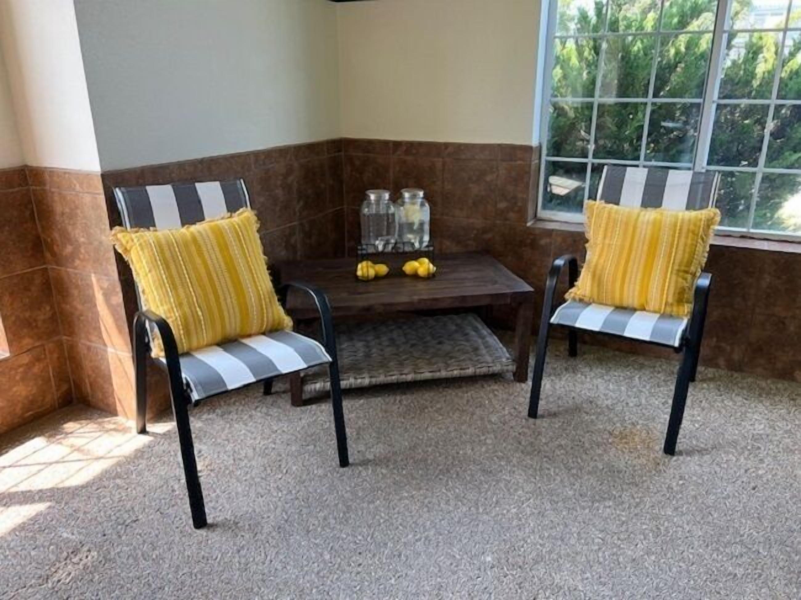A corner seating area with two chairs and a table, featuring a view through a window.
