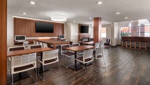 A conference room with multiple tables and chairs, a large screen, and a fireplace. - Microtel Inn & Suites by Wyndham Tifton (Tifton)