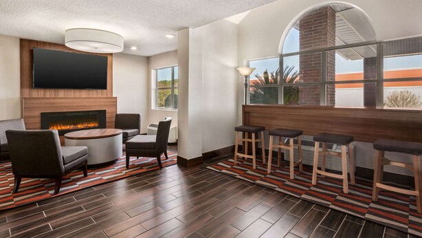 A modern living room with a fireplace, comfortable seating, and a large TV. - Microtel Inn & Suites by Wyndham Tifton (Tifton)