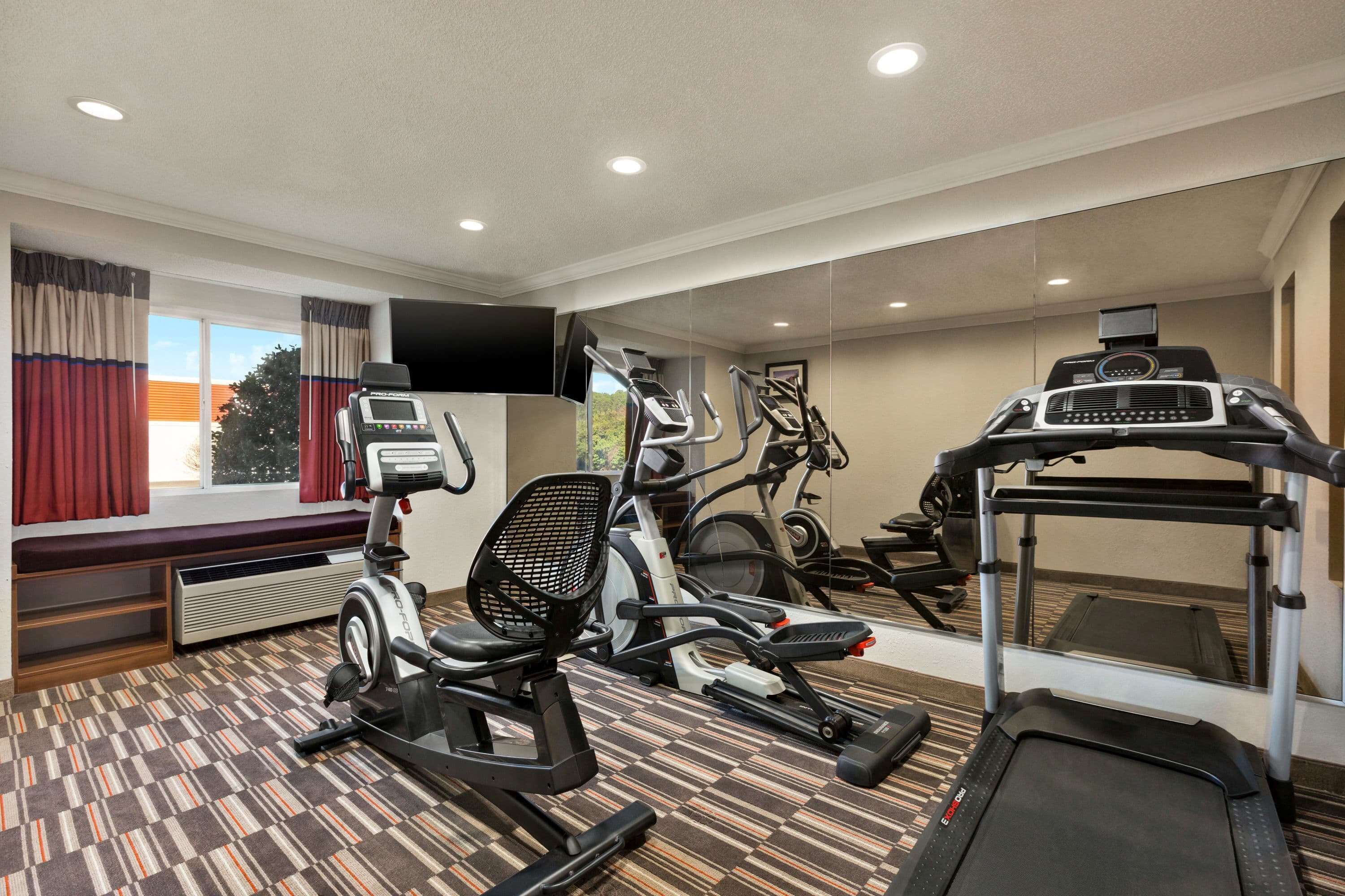 Een hotelgym met hometrainers, een loopband en een roeimachine.