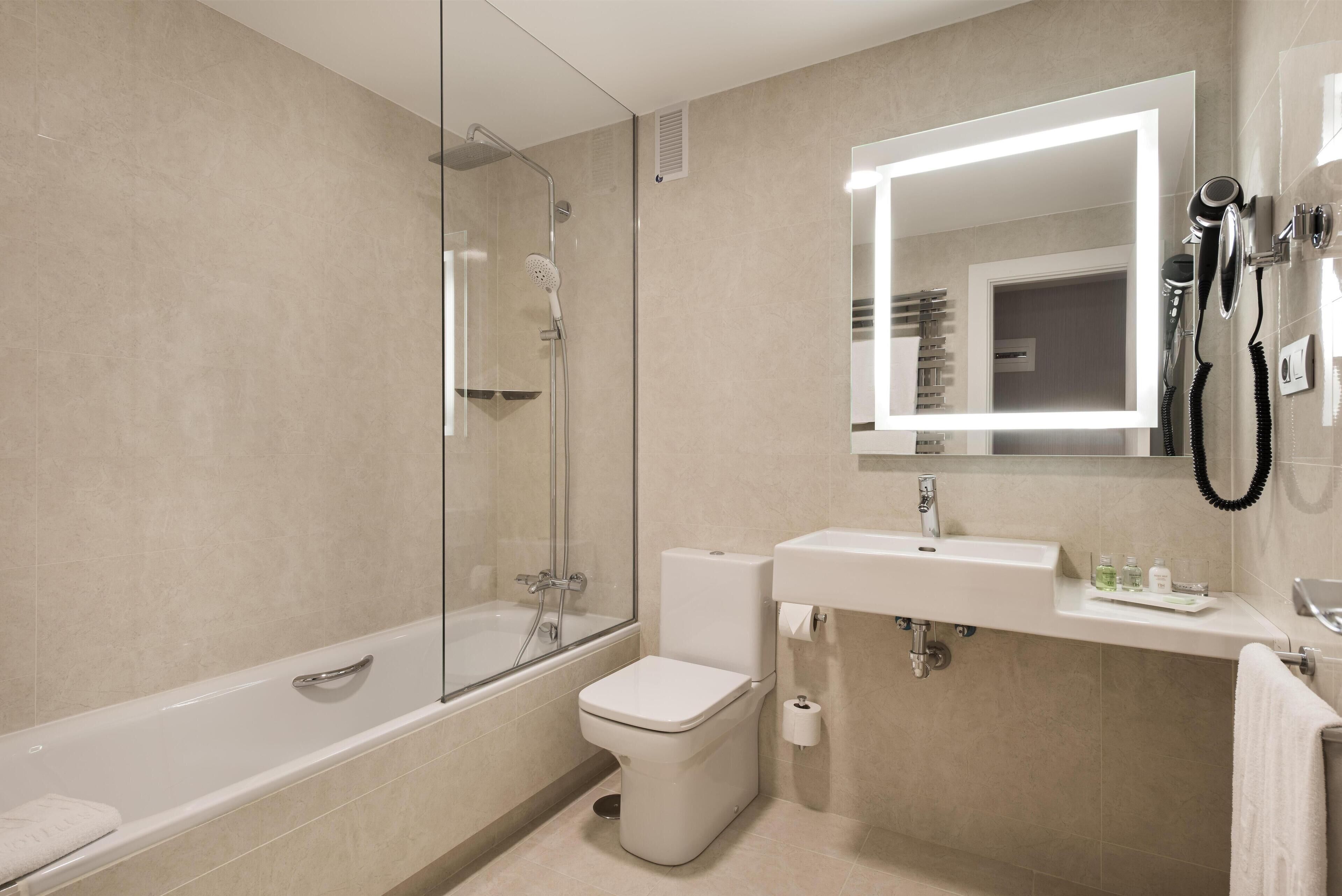 Un baño moderno con ducha de vidrio, inodoro blanco y lavabo con espejo.