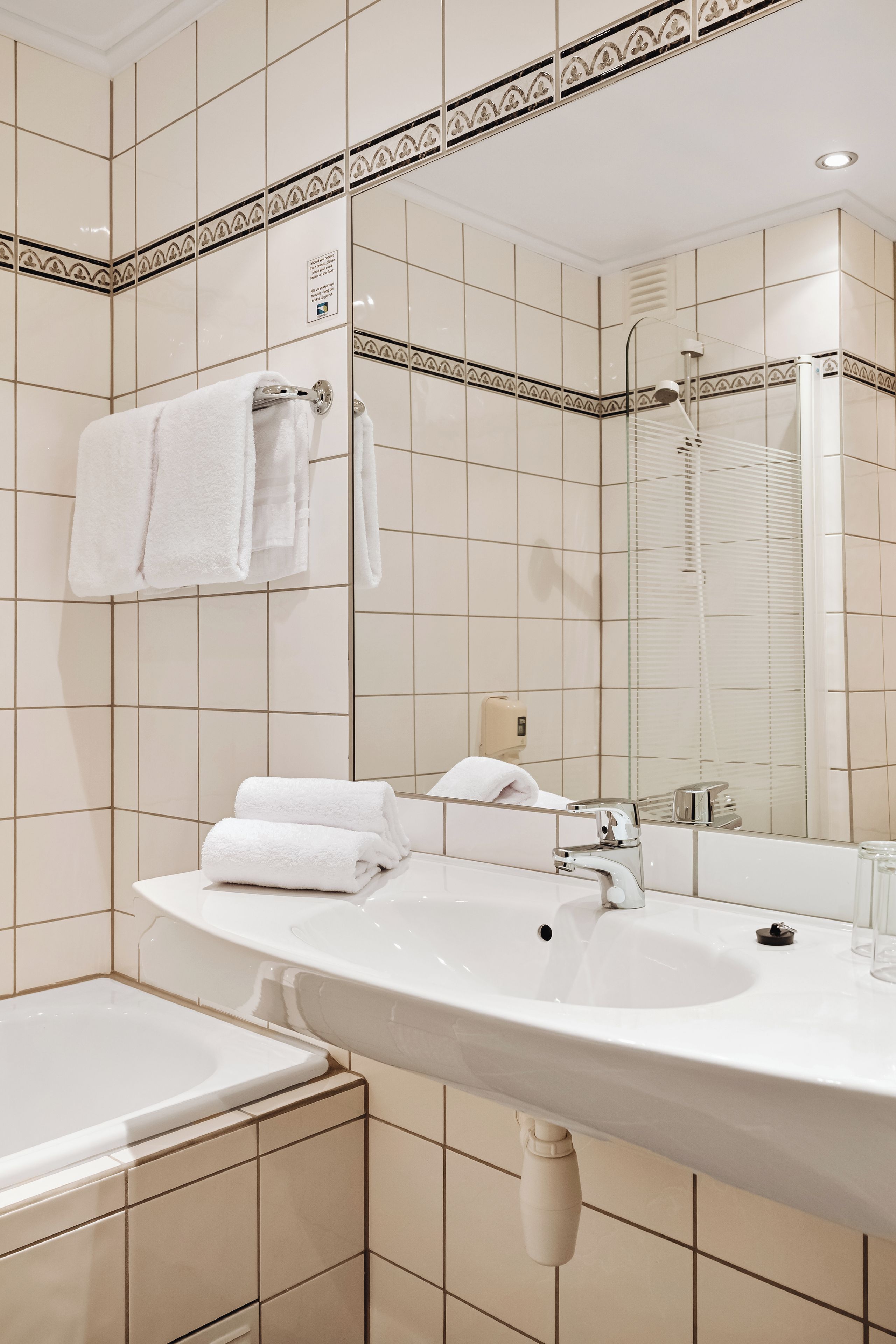 A bathroom with a large sink, mirror, and bathtub.