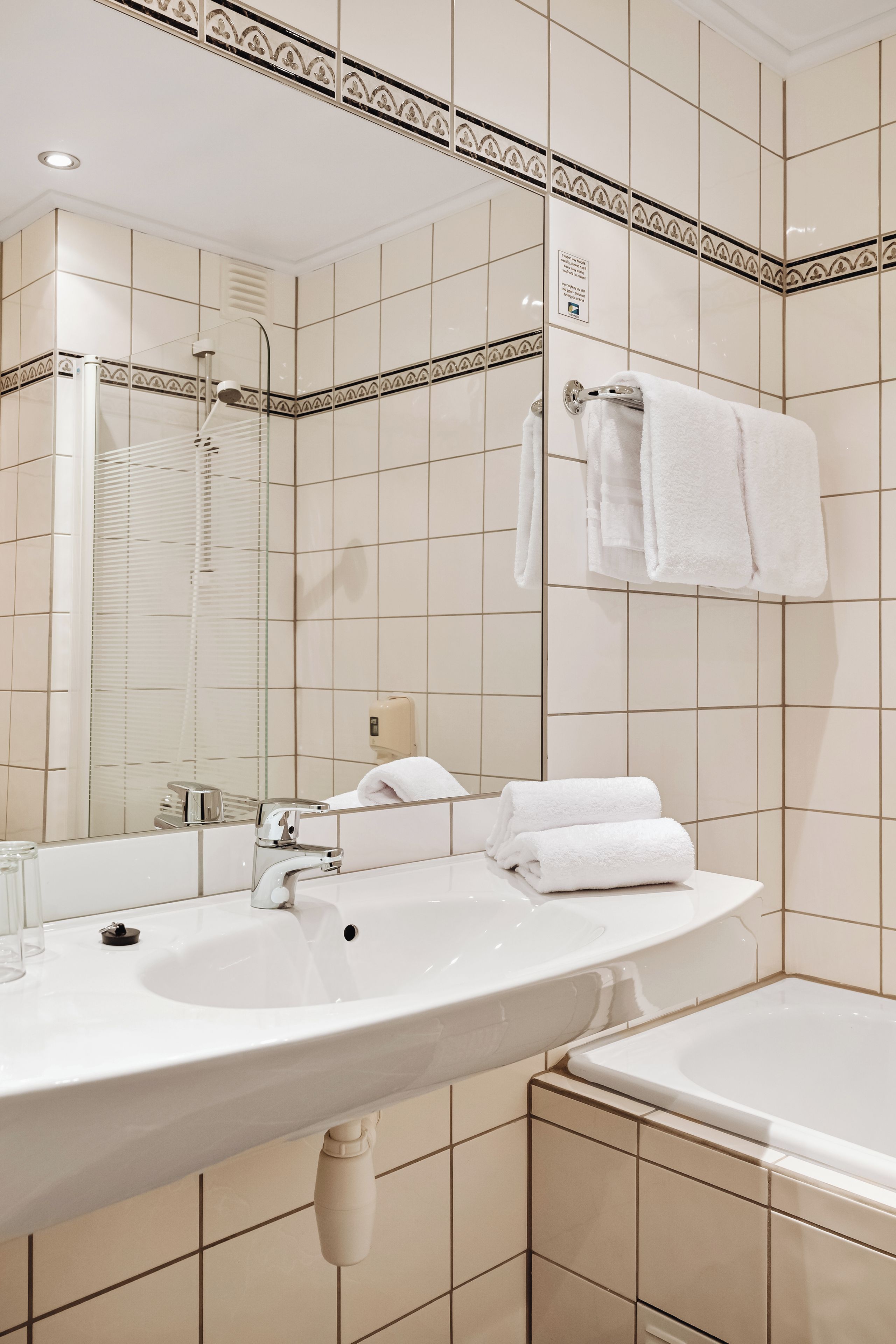 A bathroom with a sink, mirror, and bathtub.