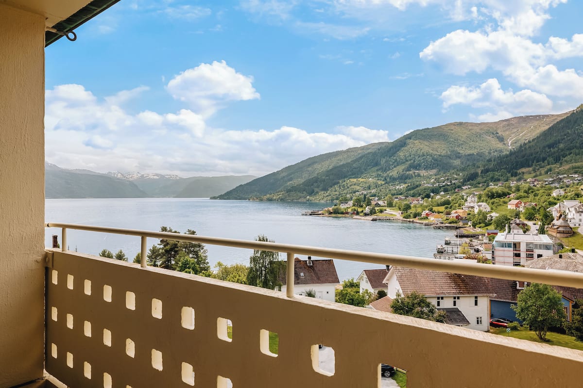 Un balcón con vista a un lago, casas y montañas.