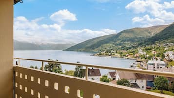A balcony with a view of a lake, houses, and mountains.