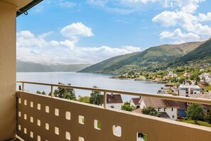 A balcony with a view of a lake, houses, and mountains.