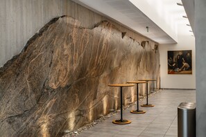 A modern interior with a large stone wall, minimalist tables, and a painting on the wall. - Kviknes (Sogndal)