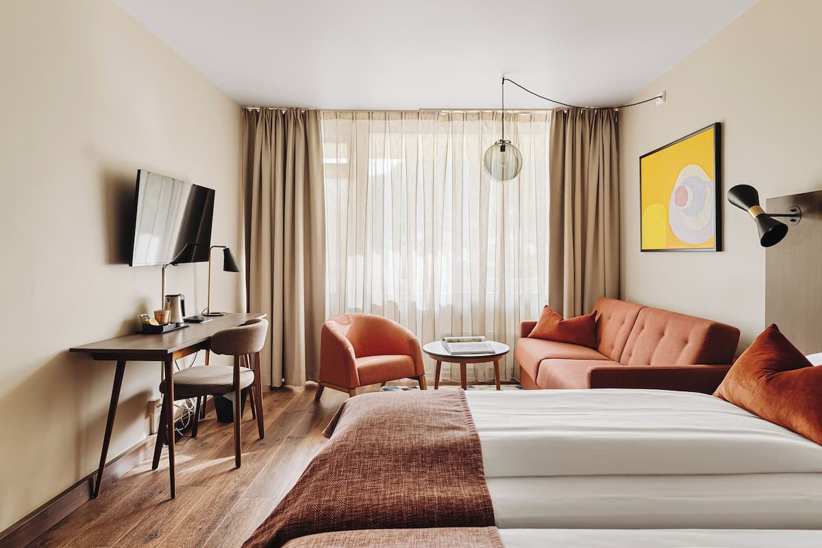Una habitación de hotel con una cama, un escritorio, una silla, un sofá y un televisor.