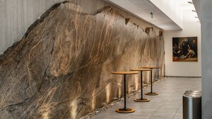 A modern interior with a large stone wall, minimalist tables, and a painting on the wall.