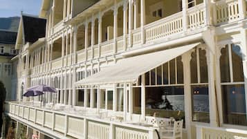 A multi-story building with balconies, a covered walkway, and a view of the water.