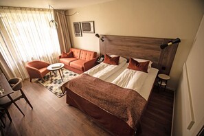 A hotel room with a large bed, a sofa, a small table, and a chair. - Kviknes (Sogndal)