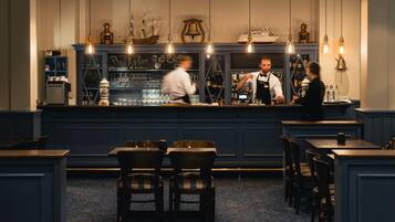 A bar area with a counter, bar stools, and a seating area with tables and chairs.