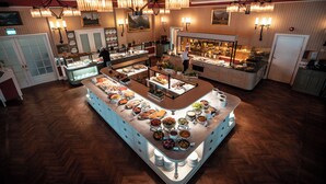 A buffet area with multiple food stations, a central serving counter, and a chef preparing food.