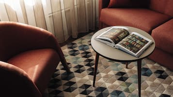 A room with a checkered floor, a round table with a book, and two red armchairs.