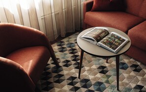 A room with a checkered floor, a round table with a book, and two red armchairs. - Kviknes (Sogndal)
