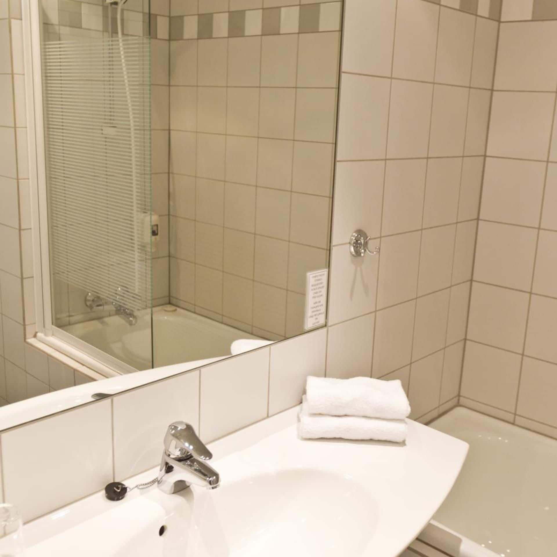 Une salle de bain avec un lavabo, un miroir et une douche.