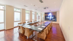 A conference room with a long table, chairs, a projector screen, and large windows. - Am Neutor Hotel Salzburg Zentrum (Salzburg)