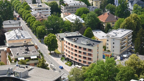 An aerial view of a residential area with multi-story buildings, a main road, and surrounding greenery. - Am Neutor Hotel Salzburg Zentrum (Salzburg)
