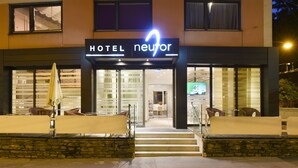 A hotel entrance with a neon sign, outdoor seating, and a staircase leading to the entrance. - Am Neutor Hotel Salzburg Zentrum (Salzburg)