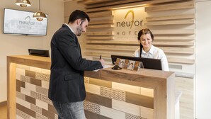 A hotel reception desk with a modern design, a digital screen, and a wooden wall with the hotel name. - Am Neutor Hotel Salzburg Zentrum (Salzburg)