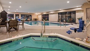 A hotel pool area with a diving board, lounge chairs, and a seating area with tables and chairs.