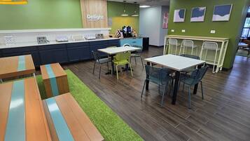 A modern cafe with a counter, seating area, and green walls.
