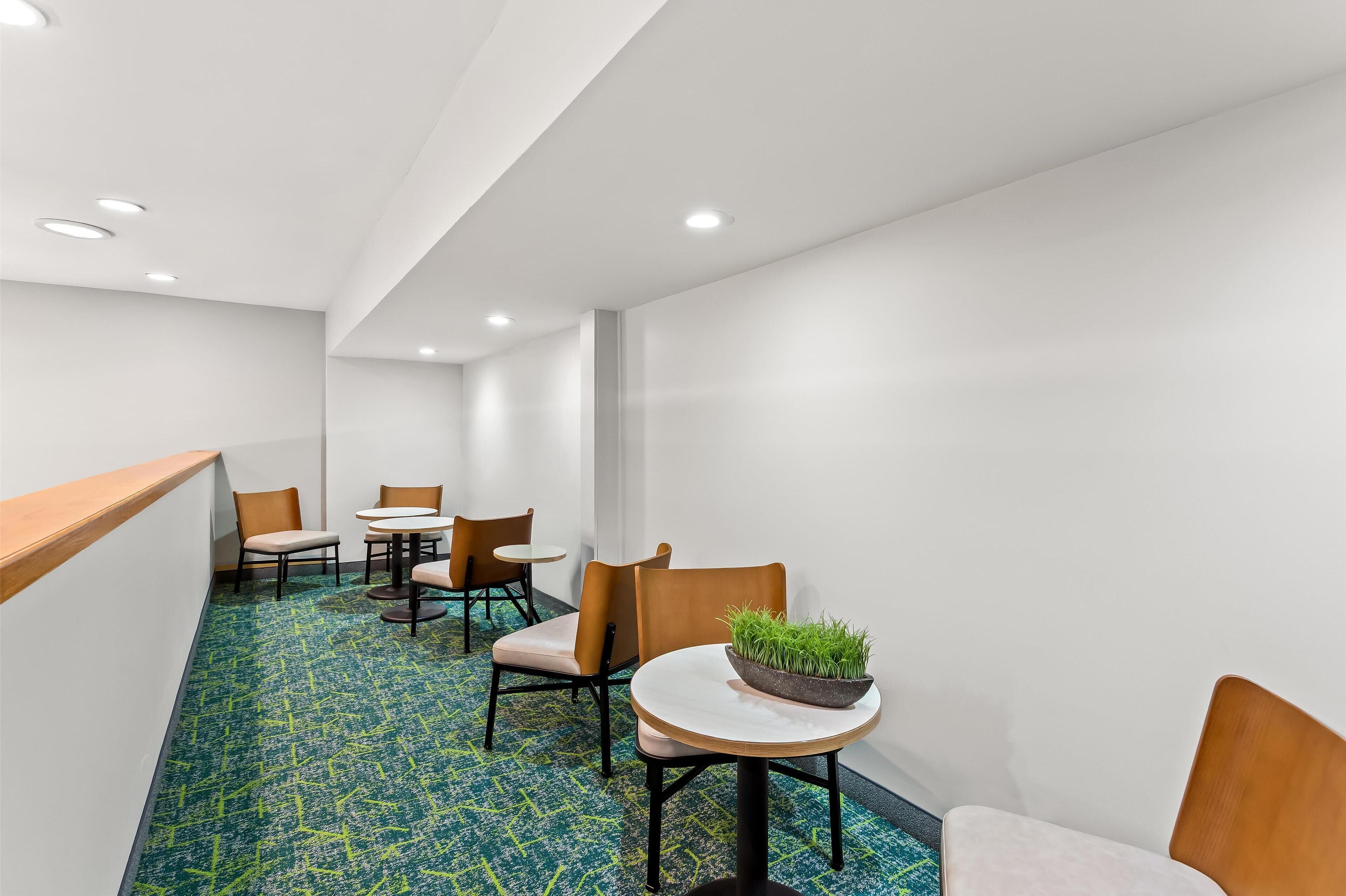 A hotel lobby with a reception desk, several chairs, and tables.