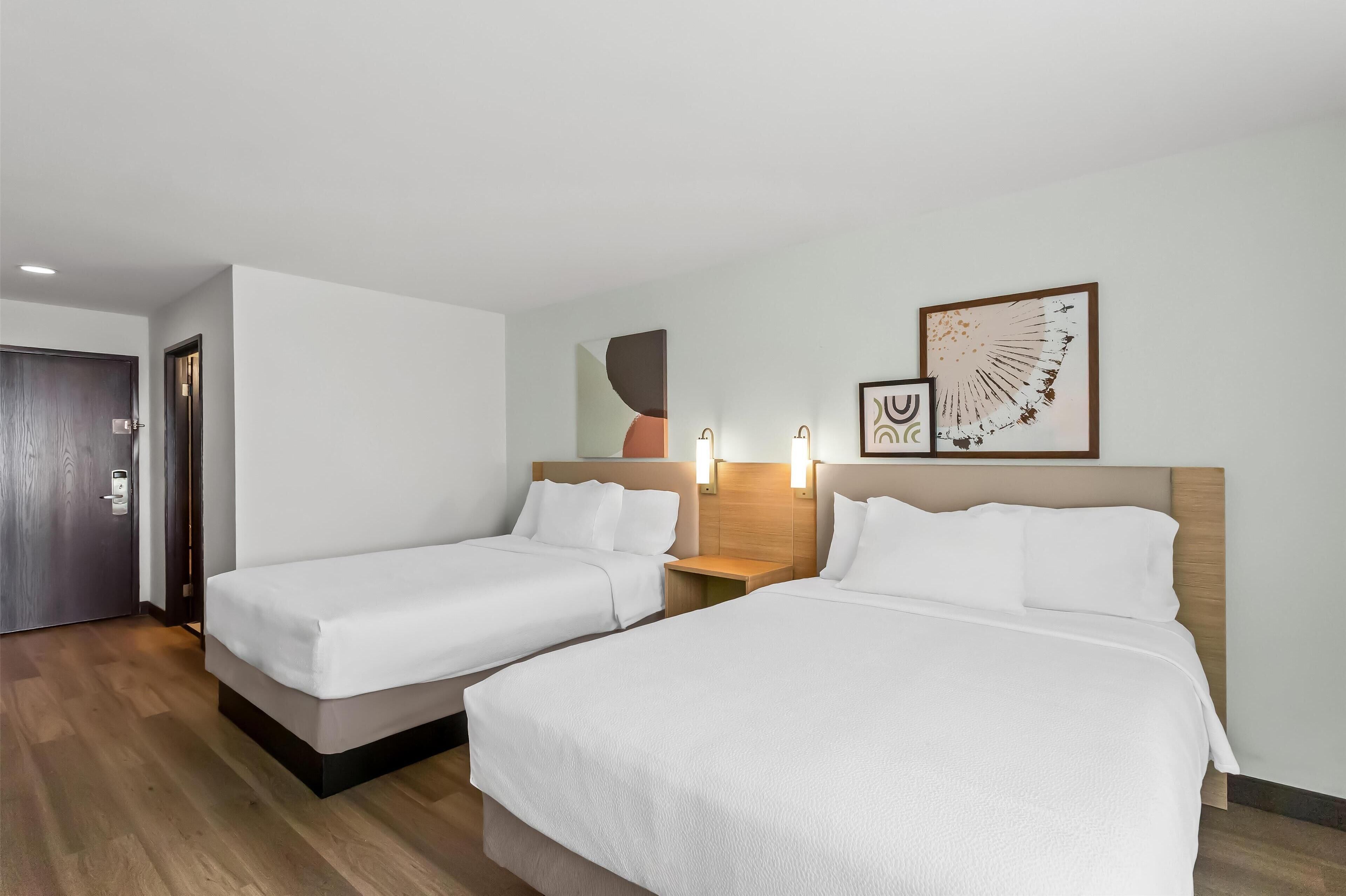 Ein Hotelzimmer mit zwei Einzelbetten, einer Holztür und Wandleuchten.