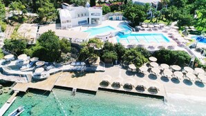 An aerial view of a resort with a large pool, sun loungers, and a beach area. - Hapimag Resort Sea Garden (Bodrum)