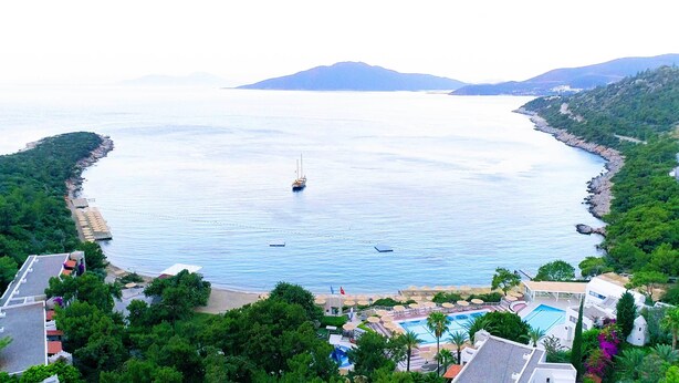A coastal resort with a swimming pool, a sailboat on the water, and lush greenery. - Hapimag Resort Sea Garden (Bodrum)