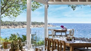 An outdoor dining area with a view of the sea, wooden tables and chairs, and a tropical fruit centerpiece. - Hapimag Resort Sea Garden (Bodrum)