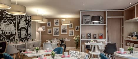 A modern dining area with patterned chairs, tables, and a wall decorated with black and white cityscape prints.