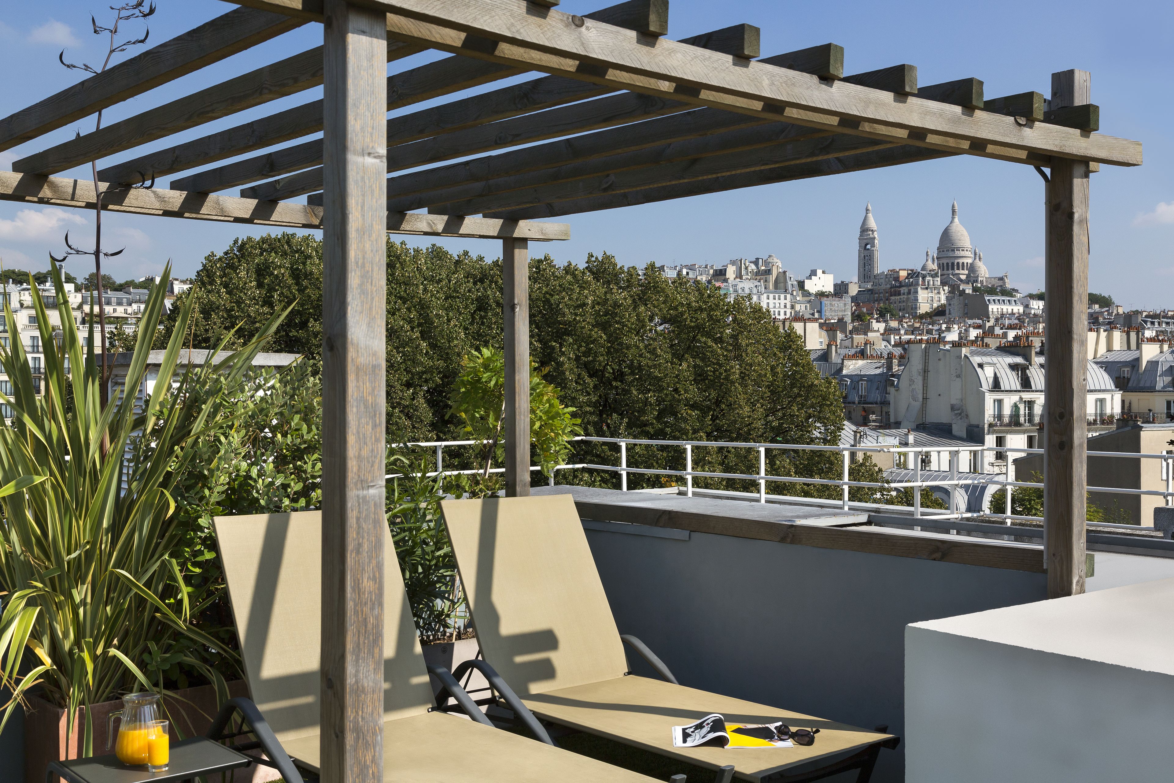 Une terrasse sur le toit, agrémentée d’une pergola, de chaises longues et offrant une vue sur le paysage urbain, avec ses bâtiments remarquables.