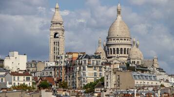 Un bâtiment historique doté de toits en dôme et d’une tour horloge, entouré d’immeubles d’habitation.